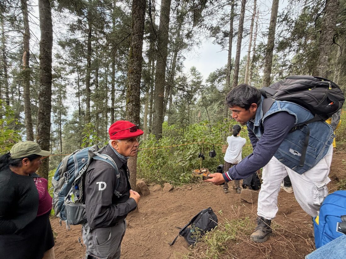 Two mountain guides on the trail, one carrying gear and tending to the group